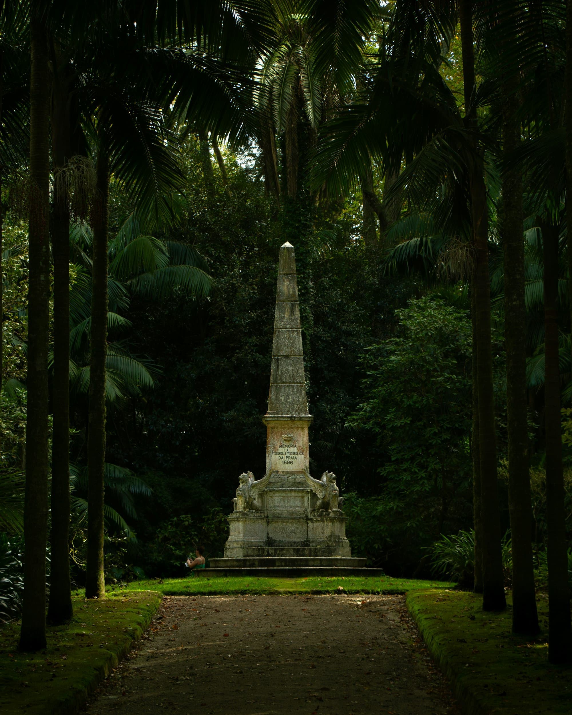 Stone obelisk standing in a lush green forest