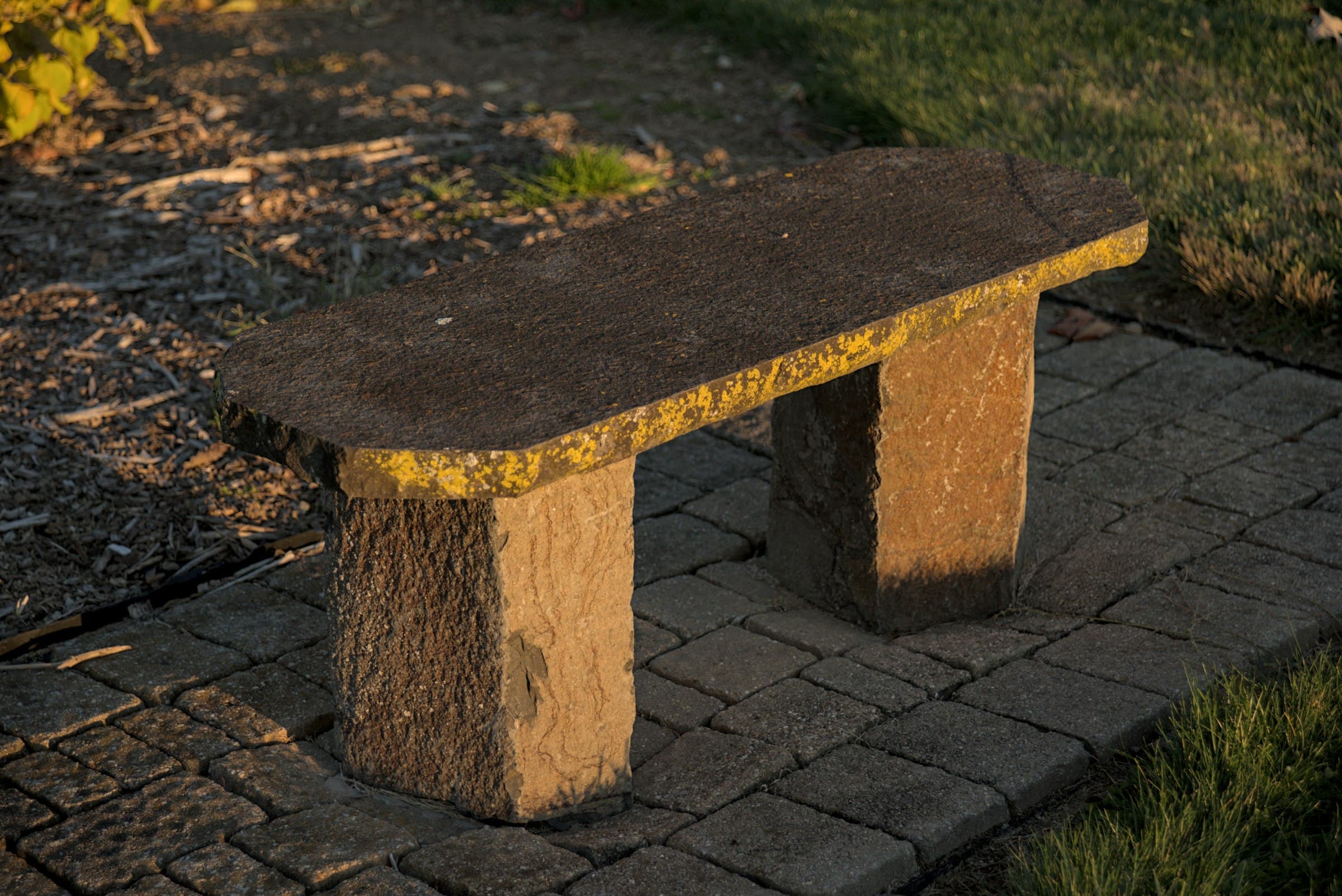 Granite bench on a sunlit paved walkway