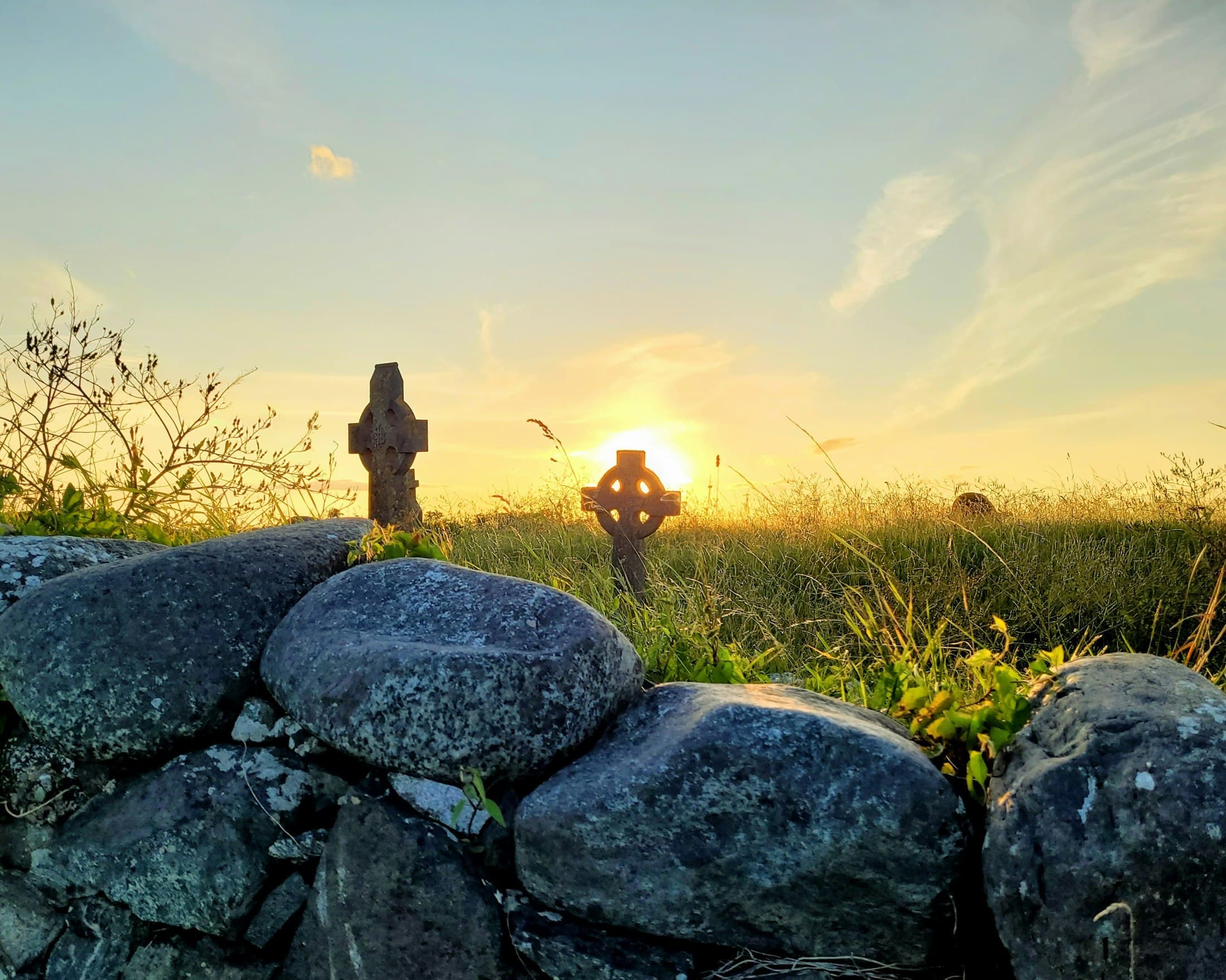 Fieldstone wall and cross at sunrise