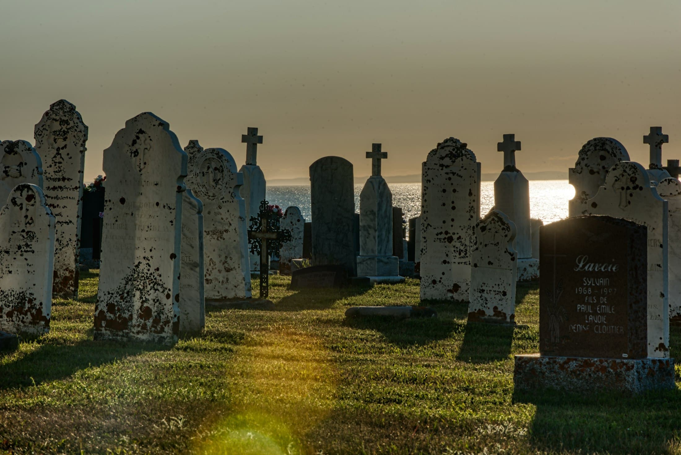 Row of upright headstones silhouetted at sunset